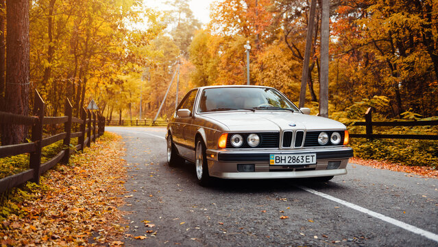 Silver classic BMW 6-series E24 coupe. Front view of 1980-s "sharknose" BMW with round headlights on golden autumn day in a forest. Kyiv, Ukraine - October 20 2017.