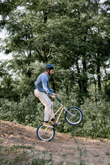 Young sportive man riding bmx bike outdoors, training, doing difficult and dangerous tricks with...