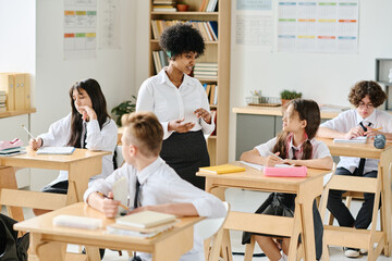 African American teacher talking to pupils at lesson at school