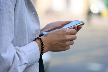 Girl standing with smartphone on a street on cars background. Mobile communication in city