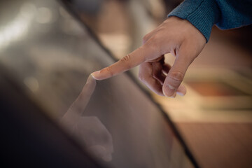 a person uses an interactive  touchscreen display of an electronic kiosk at an exhibition or in a museum - scrolling, touch gesture. Education, technology concept