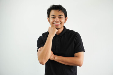handsome young man leaning his chin on his fist, crossing his arms and smiling wide wearing black polo t shirt isolated on white background
