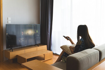 People holding remote and watching TV on sofa at home.