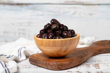 Black olives at wooden bowl. Olives on a white wood background. Mediterranean food. vegan food