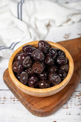 Black olives at wooden bowl. Olives on a white wood background. Mediterranean food. vegan food. Close up