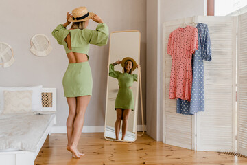 young pretty woman in green dress trying on style trend dress looking in mirror