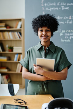 Portrait of young African American IT teacher with tablet pc smiling at camera while standing in class