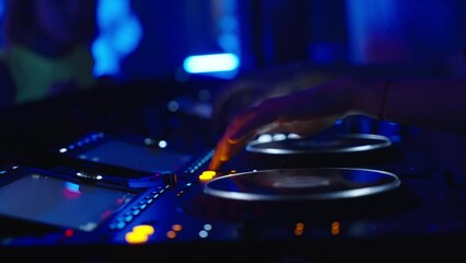 In the dark, a DJ console in a nightclub. Female DJ hands control the DJ console while dancing in a disco