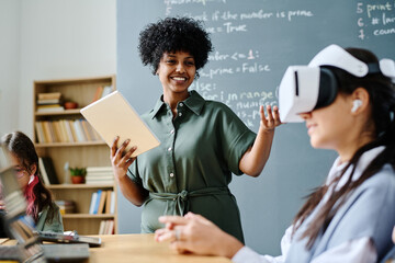 Smiling African American teacher having IT lesson with students while they using VR glasses