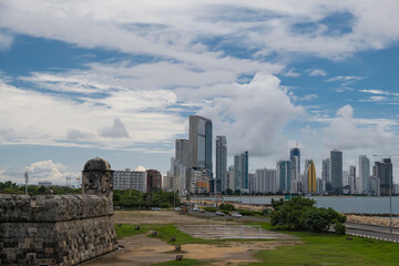 Fototapeta na wymiar City skyline with many tall highrise office, business and condo skyscrapers at the waterfront by ocean, shot on a sunny day from Old City Fort walls, Cartagena Colombia.