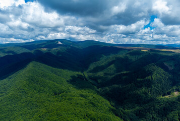 Naklejka premium Aerial landscape with the shadows of the clouds on the forest and mountains