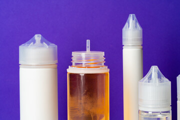Electronic cigarettes liquid bottles on purple background