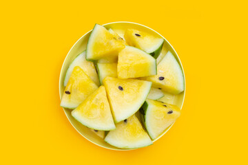 Yellow watermelon slices on yellow background.