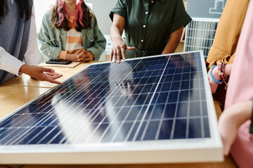 Close-up of teacher pointing at solar panel and showing the work of it to students