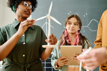 Young African American teacher talking about windmill to pupils during lesson at school