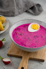 Chłodnik, Šaltibarščiai is traditional lithuanian, polish beet soup. Cold summer soup of beetroot, kefir, cucumbers, eggs, dill and potatoes in a bowl on a cutting board. Summer Healthy food. Top view