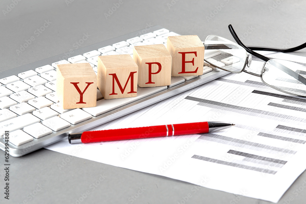 Poster ympe written on a wooden cube on the keyboard with chart on grey background