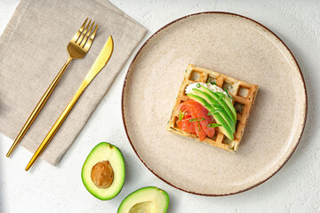waffles with avocado and salmon on a white table. composition.