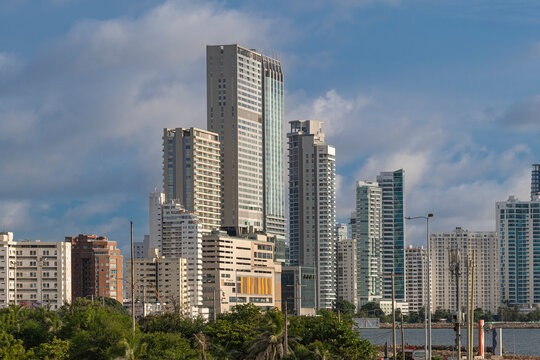City skyline with many tall highrise office, business and condo skyscrapers at the waterfront by ocean, shot on a sunny day from Old City Fort walls, Cartagena Colombia.