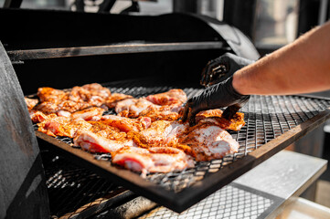 Chef hand cooking grilled chicken meat in BBQ smoker.