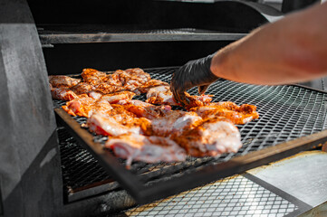 Chef hand cooking grilled chicken meat in BBQ smoker.