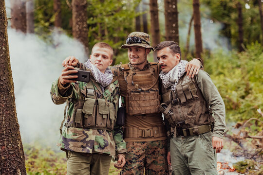 Team of soldiers and terrorist taking selfie with smartphone in the forest