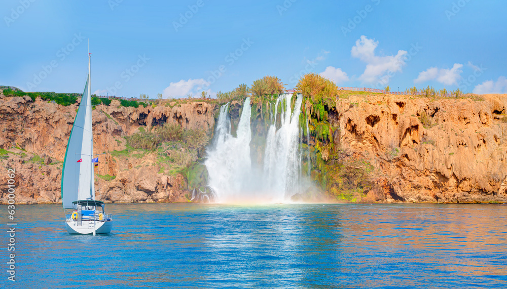 Wall mural Lonely yacht sailing in the Mediterranean sea - Powerful Duden waterfall with rainbow, a water stream breaks from a high cliff - Antalya, Turkey