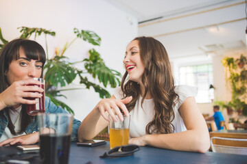 Three young women sitting indoors bar chatting and talking