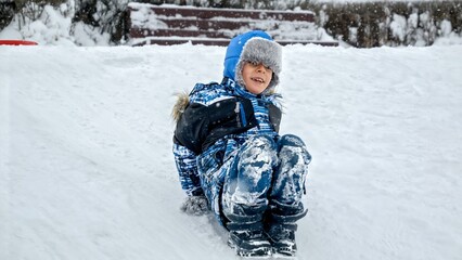 Joy of a child as he sleds down a snowy hill on his feet, with the footage slowed down to...