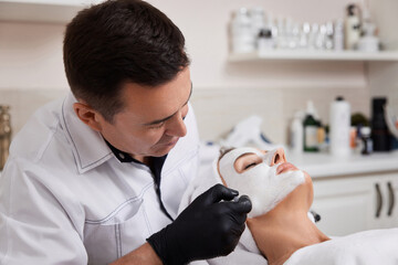 beautician applies the mask to face of woman in the spa salon. skin care