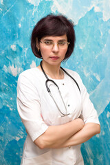 Portrait female doctor 40-44 years old near a blue wall.