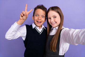 Photo of positive schoolkids blogging selfie make v sign isolated on vibrant color background