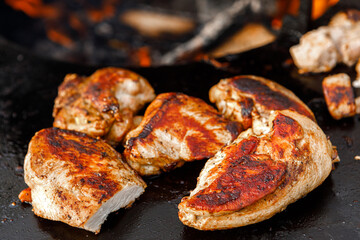 Pieces of grilled chicken meat lie on the grill.