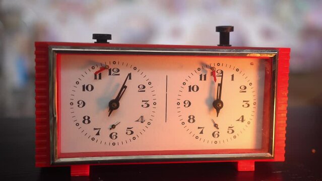 View of chess clock. Vintage chess timer. Player's hand presses on button. Second clock pointer moves measuring player move period on face of vintage chess timer