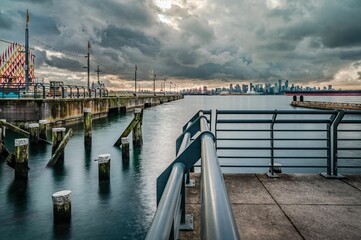 Fototapeta premium A long exposure of North Vancouver shipyard pier with poles on the water and a big cloudy sky