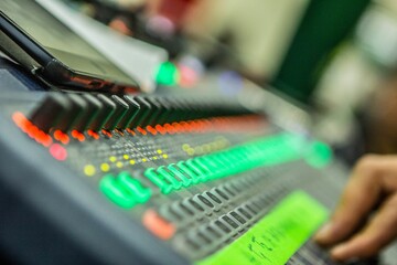 Person operating a mixing desk with their hands making adjustments to the knobs