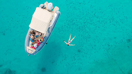 View of a private recreational boat with people swimming	