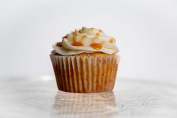Freshly-baked cupcake with a smooth, swirled layer of white frosting on top