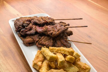 Close-up image of a dinner plate featuring an assortment of grilled meat and french fries