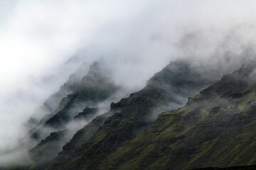 Scenic landscape on a cloudy day featuring a majestic mountain range in fog, Iceland