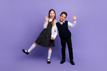 Photo of positive schoolkids have fun on school first day waving hands isolated bright color background
