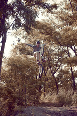 Young man, extreme sport lover riding bmx bicycle, training outdoors on hills in forest, doing tricks. High jump. Concept of active lifestyle, sport, extreme, dynamics, hobby, freestyle