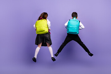 Fototapeta na wymiar Back rear photo of two schoolkids jumping wear new backpack on school discounts isolated purple color background