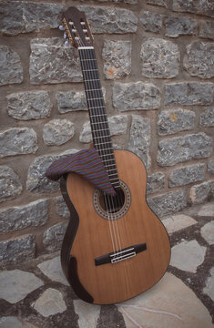 Spanish guitar leaning against a stone wall with a "cachirulo".