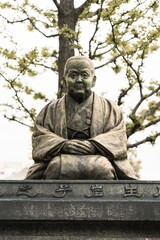Fototapeta premium Japanese statue in a grassy field surrounded by trees