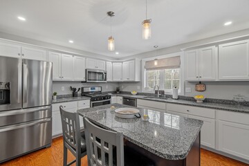 Kitchen with white cabinets, granite countertop, and modern appliances.