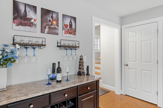 Home bar with wine glasses and pictures on the wall.