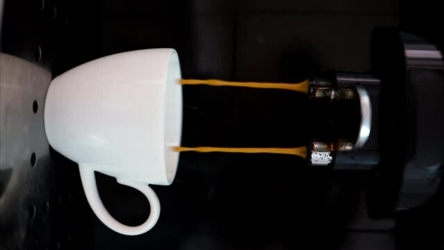 Coffee machine pouring arabica into a white espresso cup, slow motion