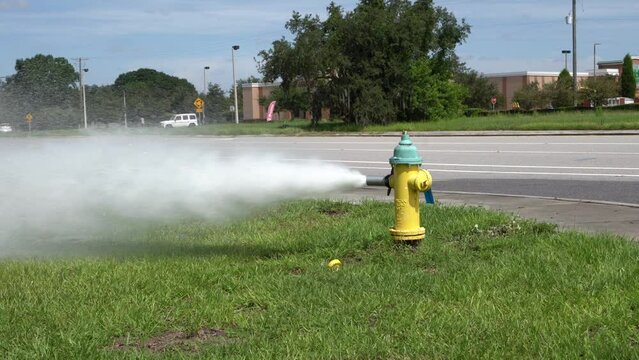 fireman in action with an open yellow fire hydrant blasting water