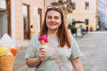 Colorful tasty ice cream cone in hand. Close up image of woman hand holding fresh waffle cone with...